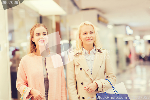 Image of happy young women with shopping bags in mall