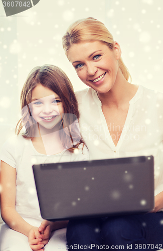 Image of smiling mother and little girl with laptop at home