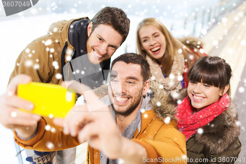 Image of happy friends with smartphone on skating rink