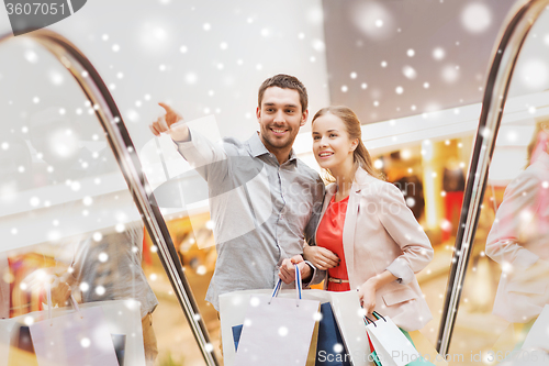 Image of couple with shopping bags on escalator in mall