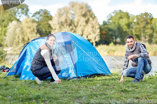 Image of happy couple setting up tent outdoors