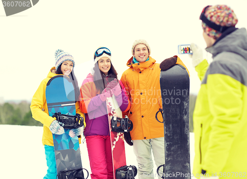 Image of happy friends with snowboards and smartphone