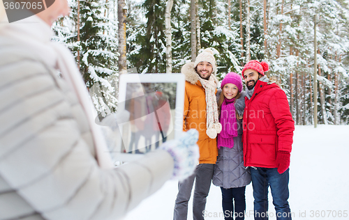 Image of smiling friends with tablet pc in winter forest