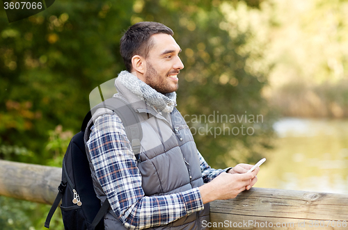 Image of happy man with backpack and smartphone outdoors