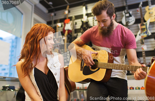 Image of couple of musicians with guitar at music store