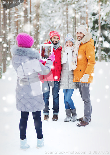Image of smiling friends with tablet pc in winter forest