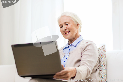 Image of happy senior woman with laptop at home