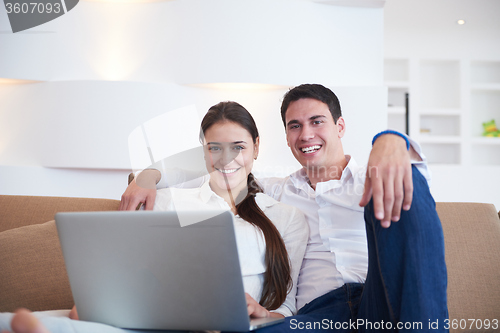 Image of relaxed young couple working on laptop computer at home