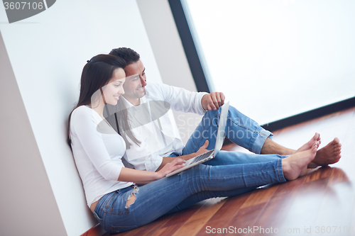 Image of relaxed young couple working on laptop computer at home