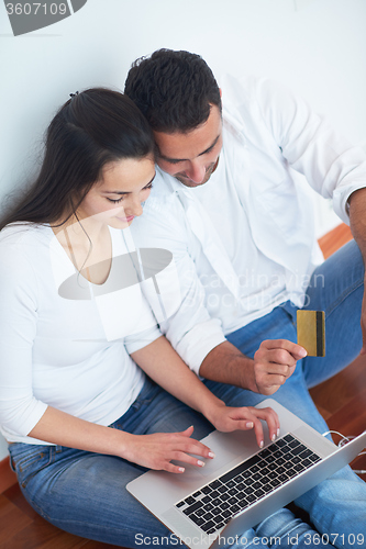 Image of relaxed young couple working on laptop computer at home