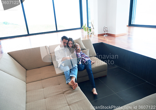 Image of relaxed young couple working on laptop computer at home