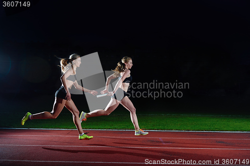 Image of athletic runners passing baton in relay race