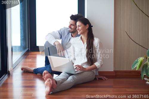 Image of relaxed young couple working on laptop computer at home