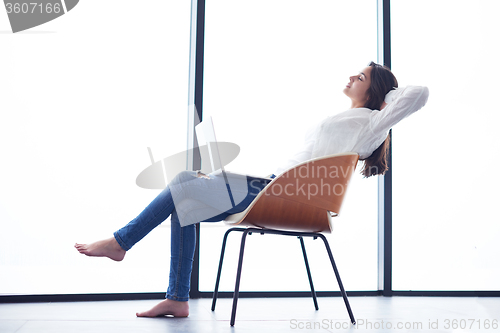 Image of relaxed young woman at home working on laptop computer