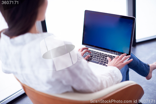 Image of relaxed young woman at home working on laptop computer