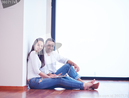 Image of relaxed young couple working on laptop computer at home