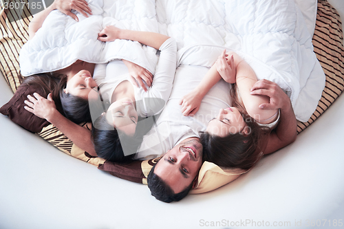 Image of handsome man in bed with three beautiful woman