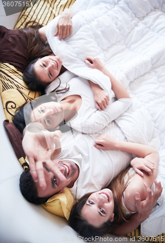 Image of handsome man in bed with three beautiful woman