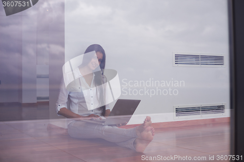 Image of relaxed young woman at home working on laptop computer