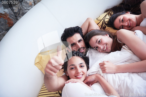 Image of handsome man in bed with three beautiful woman