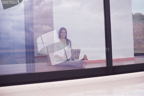 Image of relaxed young woman at home working on laptop computer