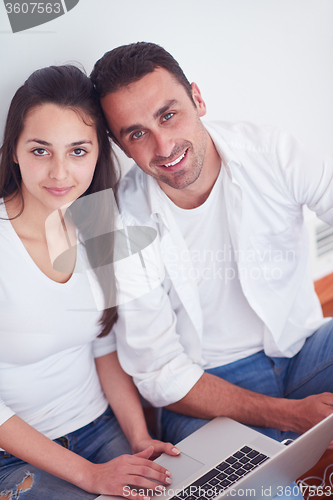 Image of relaxed young couple working on laptop computer at home