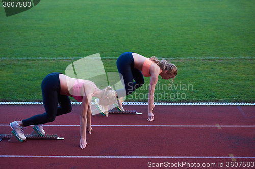 Image of woman group  running on athletics race track from start