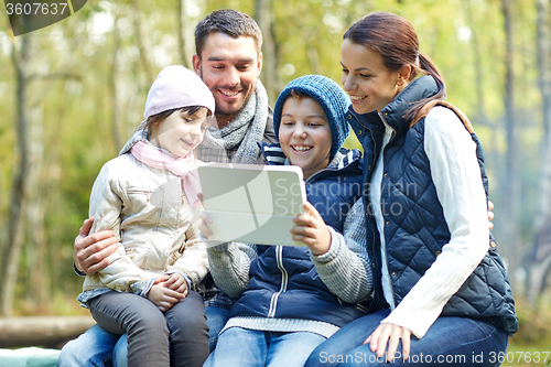 Image of family sitting on bench with tablet pc at camp
