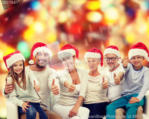 Image of happy family in santa hats showing thumbs up