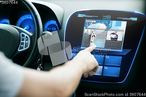 Image of male hand pointing finger to monitor on car panel