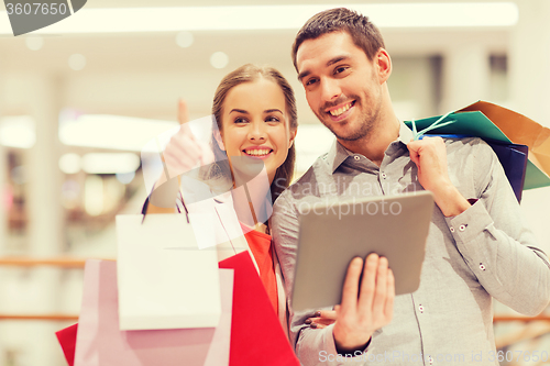 Image of couple with tablet pc and shopping bags in mall