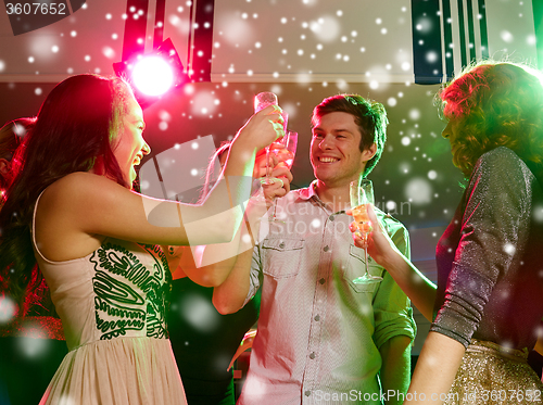 Image of smiling friends with glasses of champagne in club