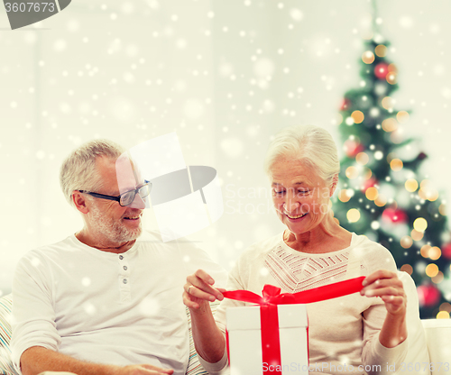 Image of happy senior couple with gift box at home