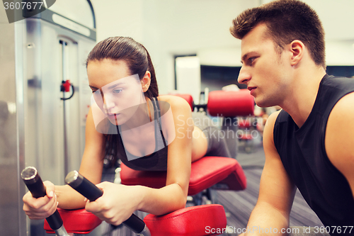 Image of young woman with trainer exercising on gym machine