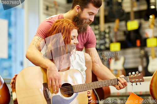 Image of couple of musicians with guitar at music store