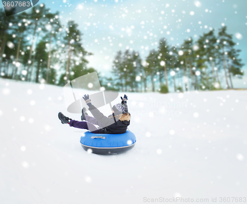 Image of happy young man sliding down on snow tube