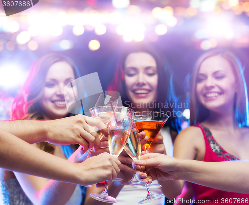 Image of happy friends clinking glasses at night club