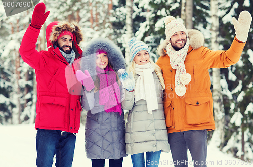 Image of group of friends waving hands in winter forest