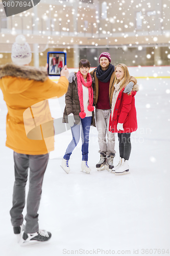 Image of happy friends taking photo on skating rink