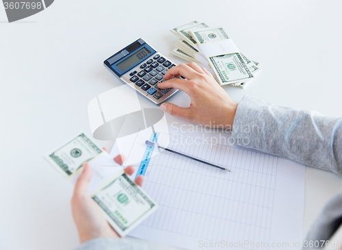 Image of close up of hands counting money with calculator