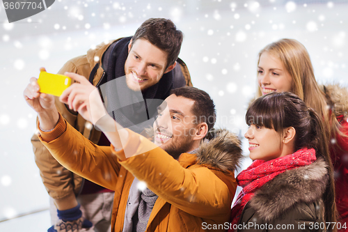 Image of happy friends with smartphone on skating rink