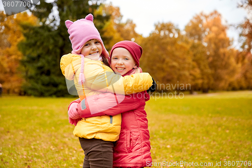 Image of two happy little girls hugging in autumn park