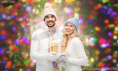 Image of smiling couple in winter clothes with gift box