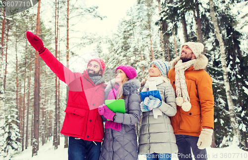 Image of smiling friends with tablet pc in winter forest