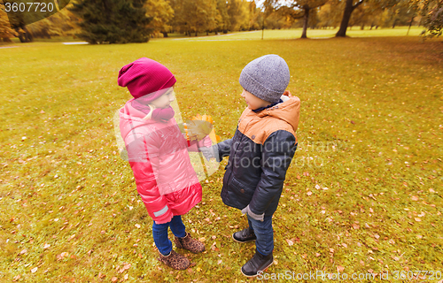 Image of little boy giving autumn maple leaves to girl