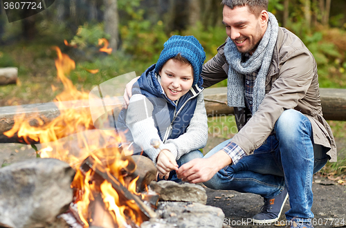 Image of father and son roasting marshmallow over campfire