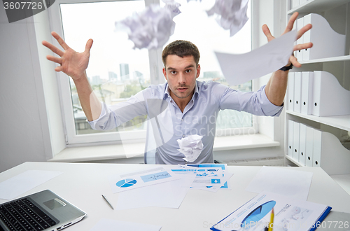 Image of angry businessman throwing papers in office