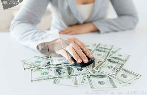 Image of close up of hand with computer mouse on money