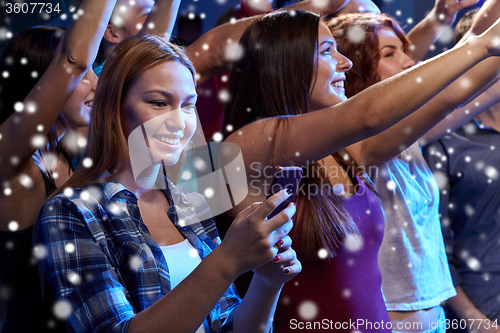 Image of woman with smartphone texting message at concert