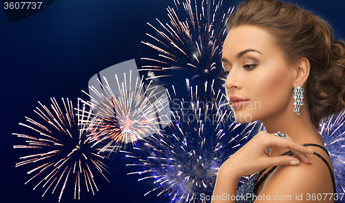 Image of beautiful woman with diamond earring over firework